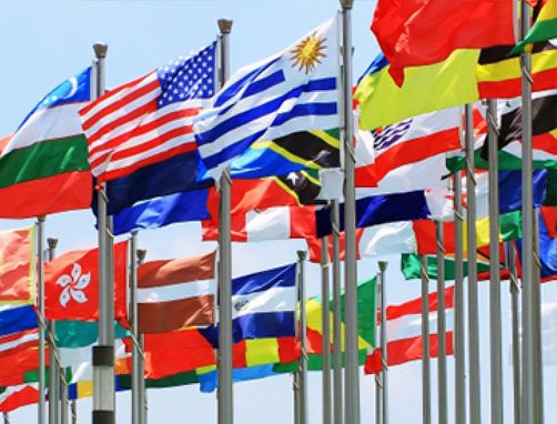 Photo depicts flags of nations around the globe waving in a breeze.